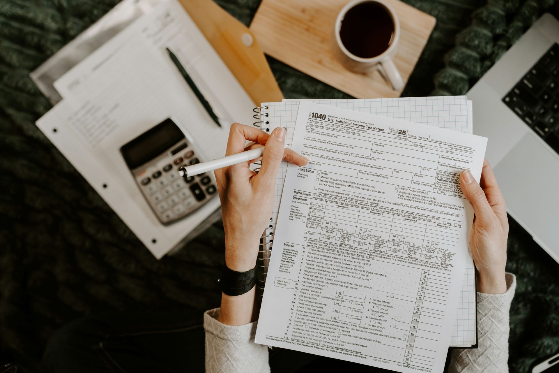 Person reviewing documents with calculator and laptop